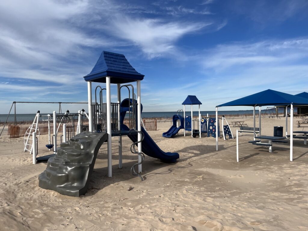 A playground with blue tents and slides on the beach.