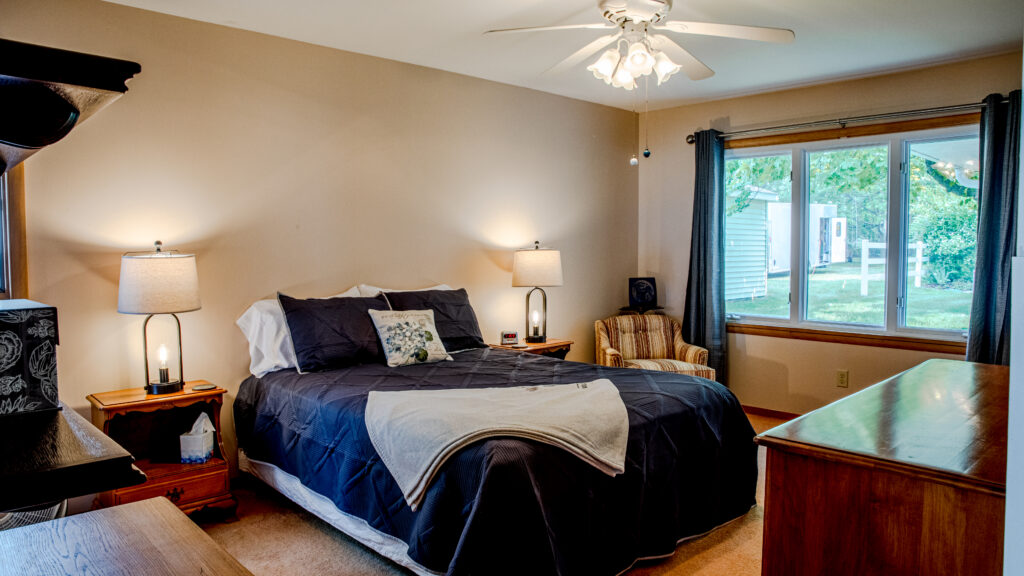 A bedroom with a bed, nightstand and lamp.