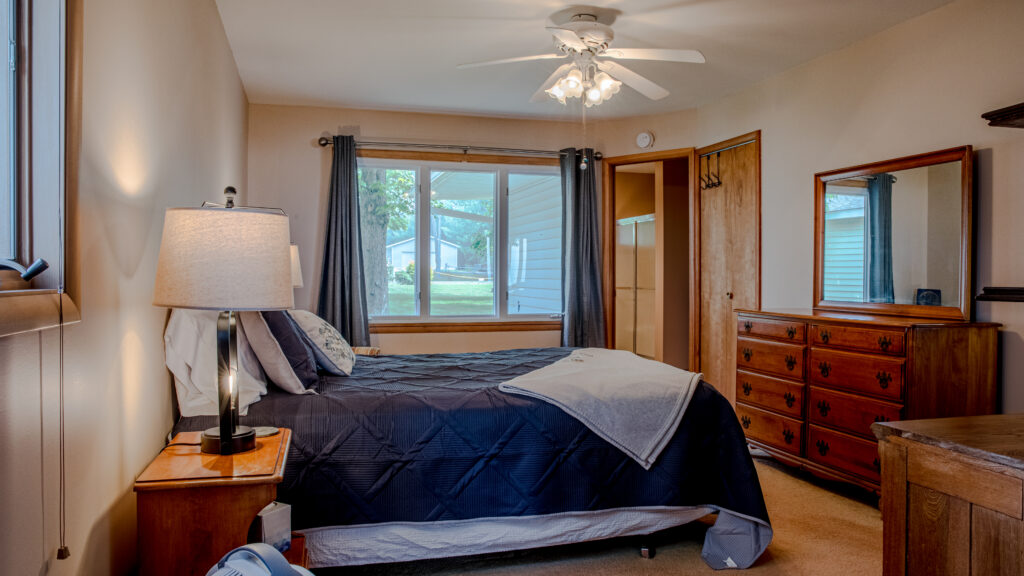 A bedroom with a bed, dresser and window.