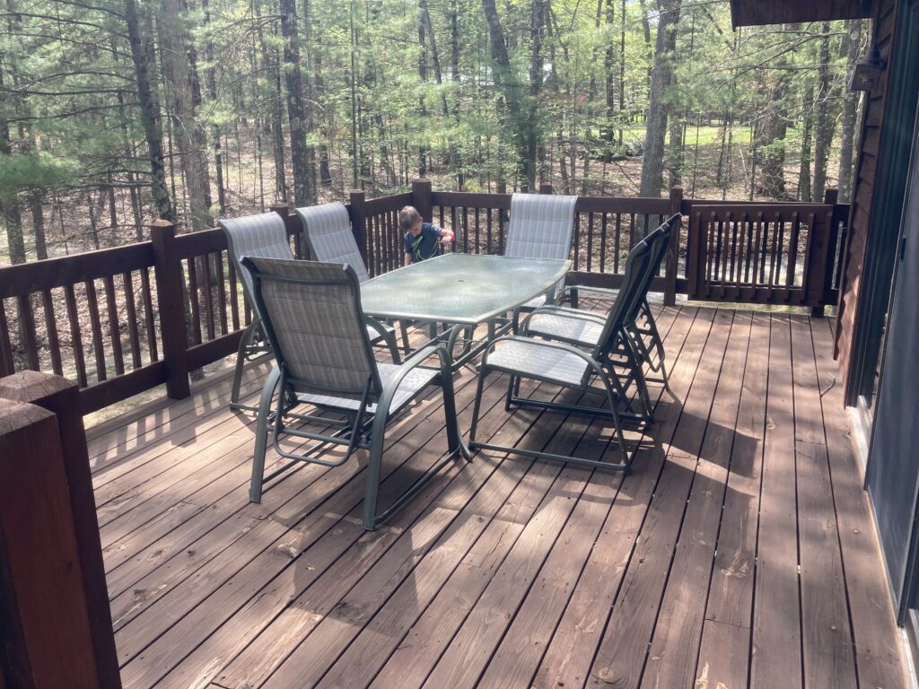 A table and chairs on the deck of a cabin.