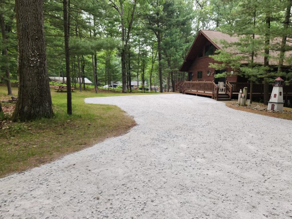 A gravel driveway leading to a log cabin.