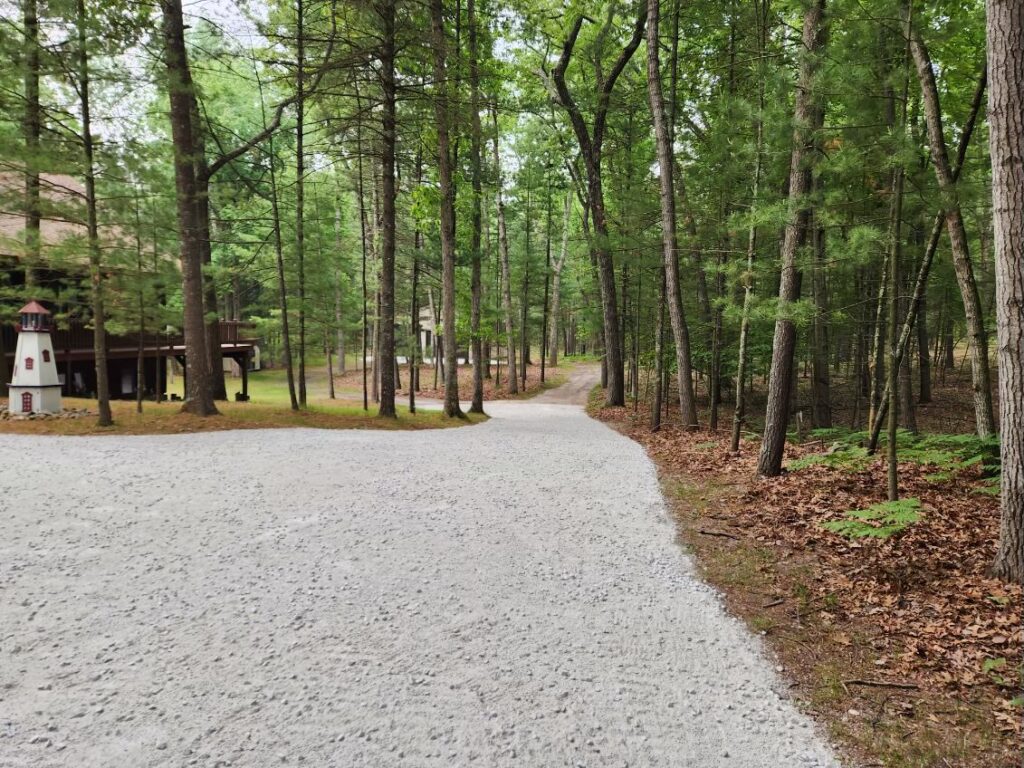 A gravel driveway leading to a log cabin.