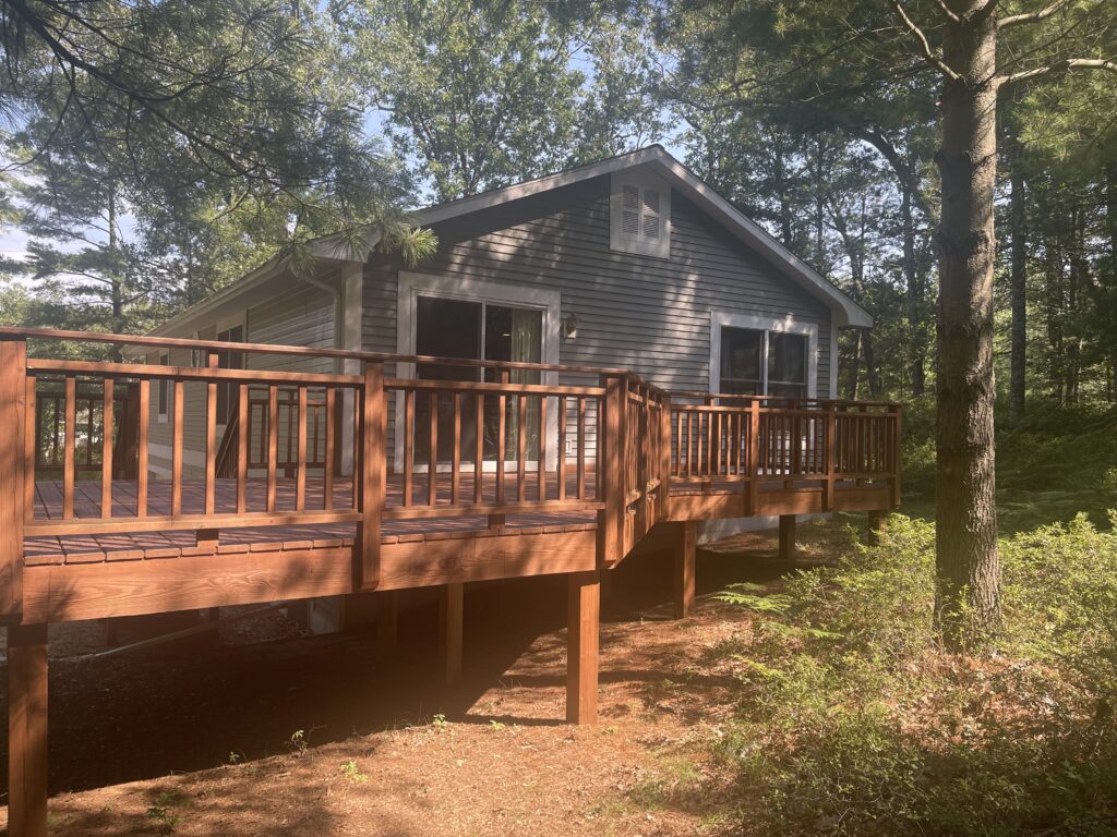 A house with a deck in the middle of the woods.