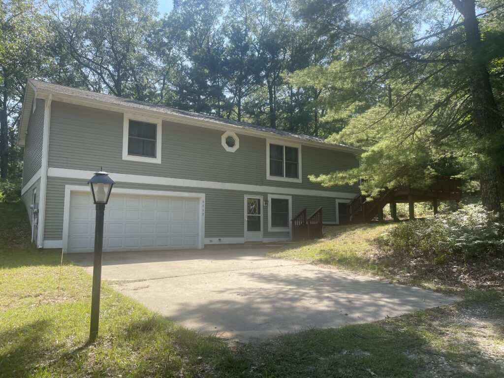 A house with a driveway and trees in the background