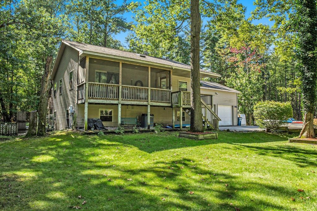 A house with a large yard and trees in the background.