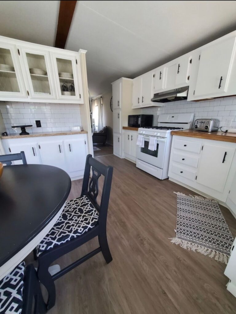 A kitchen with white cabinets and black chairs.