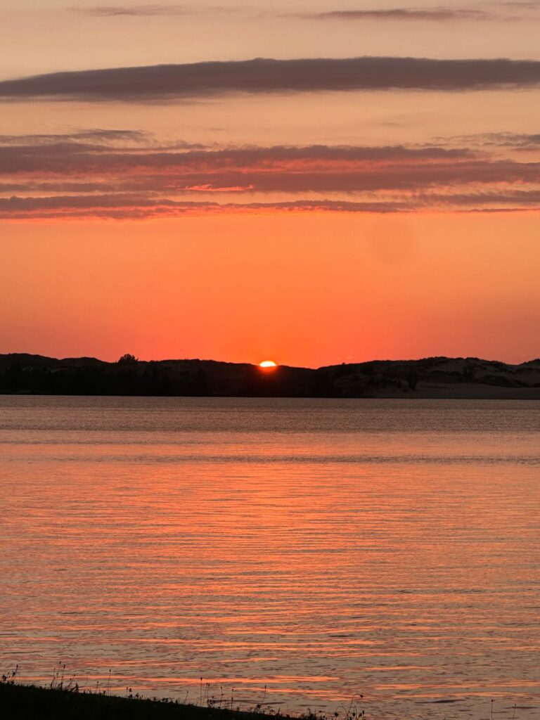 A sunset over the ocean with a large body of water.