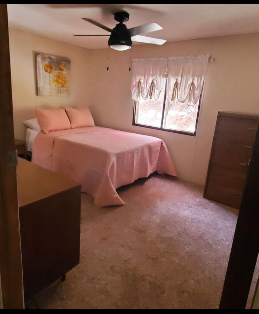 A bedroom with a bed, dresser and window.