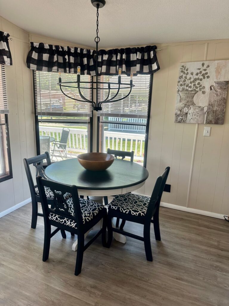 A table with four chairs in front of a window.