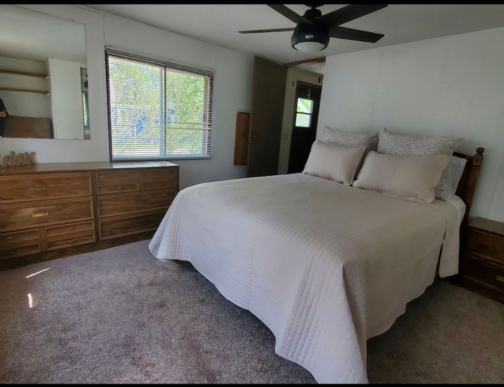 A bedroom with a bed, dresser and window.