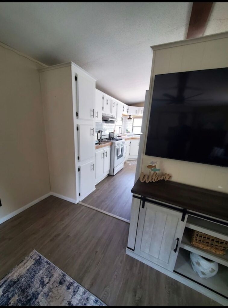 A kitchen with white cabinets and wood floors.
