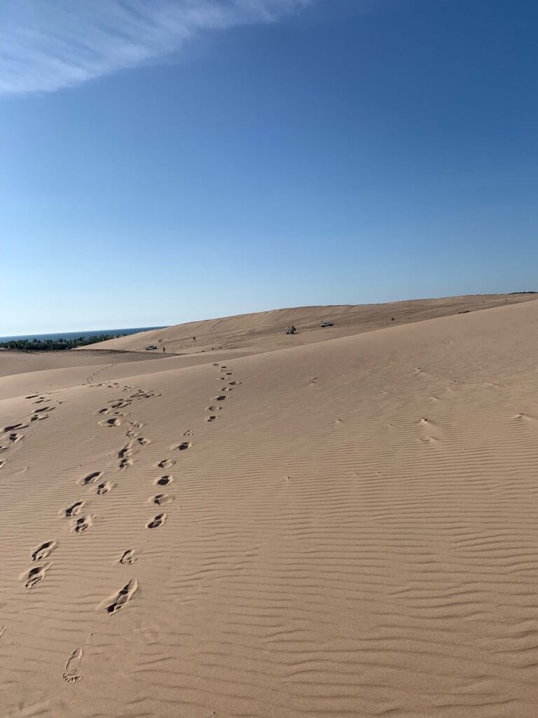 A sand dune with footprints in the middle of it.